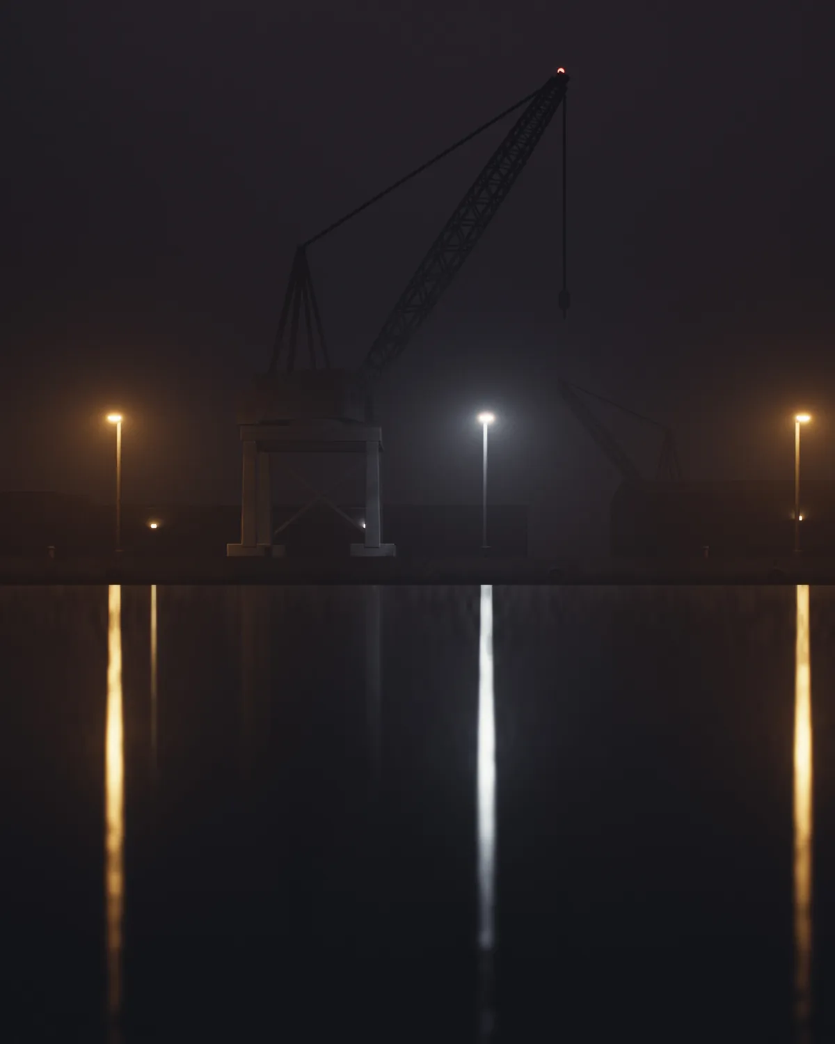 Une grue portuaire à flèche en treillis se découpe sur un ciel nocturne brun ; trois lampadaires, deux au sodium orangé et un à LED blanche, se reflètent en longues colonnes dans l’eau du bassin lissée par la pose.