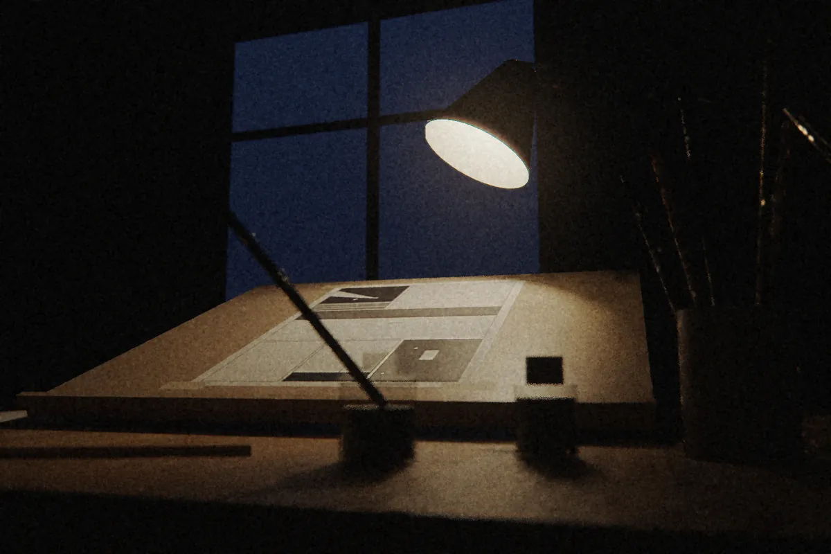 Table à dessin vue en contre-plongée, la nuit : une lampe d’architecte éclaire une planche à l’encre sur le pupitre incliné, devant des encriers et une plume ; la fenêtre est bleu nuit.